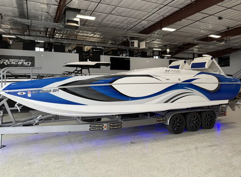 Slide: The Image of 2008 Magic 30' Sceptor boat with blue and white design on a trailer indoors. - 5