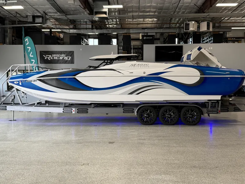 Slide: The Image of 2008 Magic 30' Sceptor boat with blue and white design on a trailer indoors. - 7
