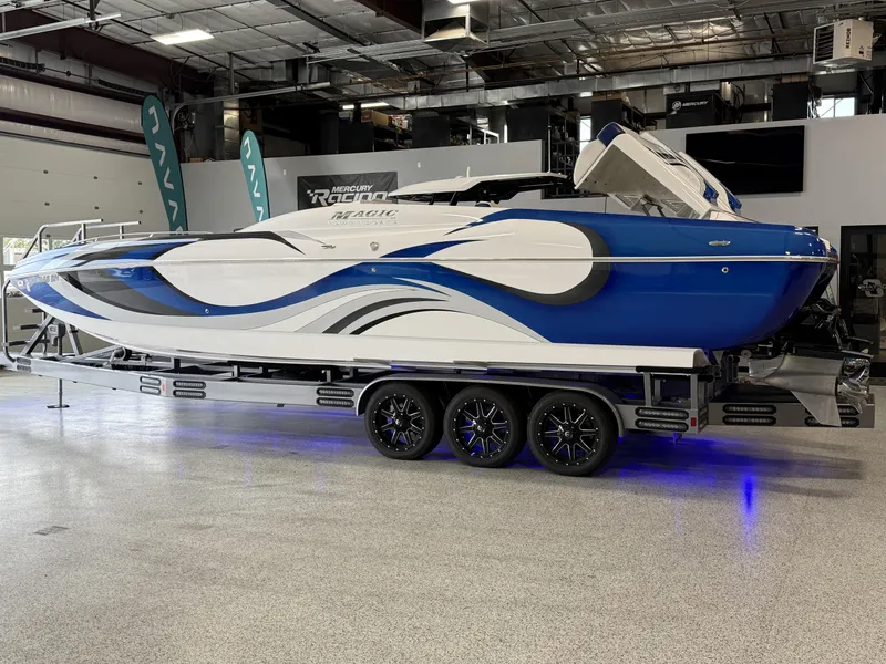 Slide: The Image of 2008 Magic 30' Sceptor boat with blue and white design on a trailer in a showroom. - 8