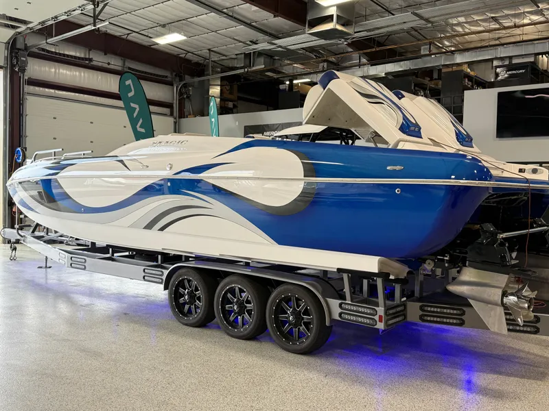 Slide: The Image of 2008 Magic 30' Sceptor boat with blue and white design on a trailer in a showroom. - 9
