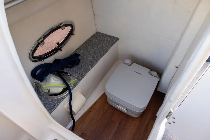 Slide: The Image of 2020 Chaparral 230 Suncoast boat interior with portable toilet and storage area. - 11