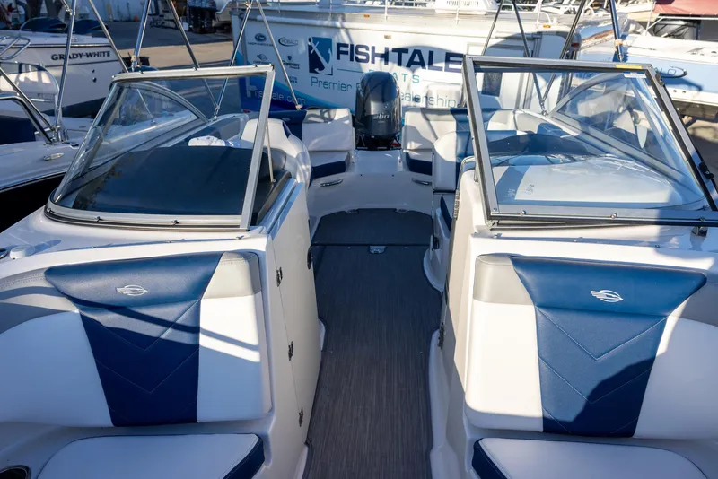 Slide: The Image of 2020 Chaparral 230 Suncoast boat interior with blue and white seating, docked at marina. - 14