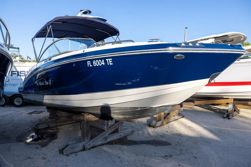 Slide: The Image of 2020 Chaparral 230 Suncoast boat in blue, displayed on wooden supports. - 2