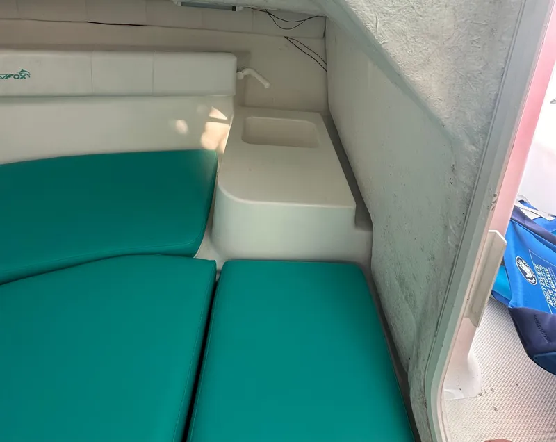 Slide: The Image of 2005 Sea Fox 257 Walk Around cabin interior with teal cushions and compact sink area. - 17