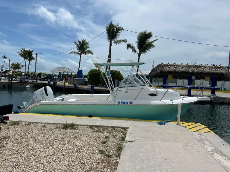 Slide: The Image of 2005 Sea Fox 257 Walk Around boat docked at a marina with palm trees. - 3