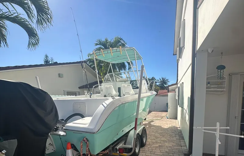 Slide: The Image of 2005 Sea Fox 257 Walk Around boat on trailer, parked beside a house under clear blue sky. - 6