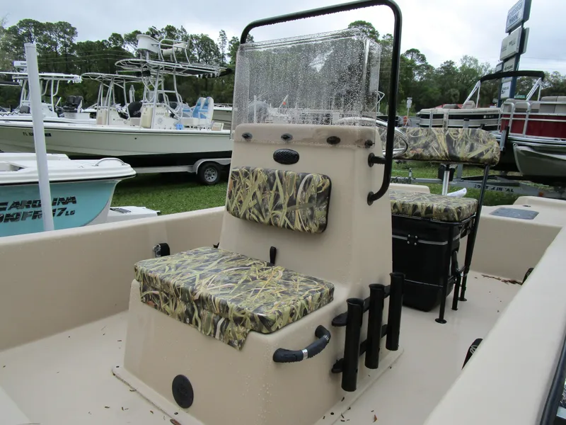 Slide: The Image of 2025 Carolina Skiff E Series E18 JVX CC boat with camouflage seating, docked outdoors. - 10