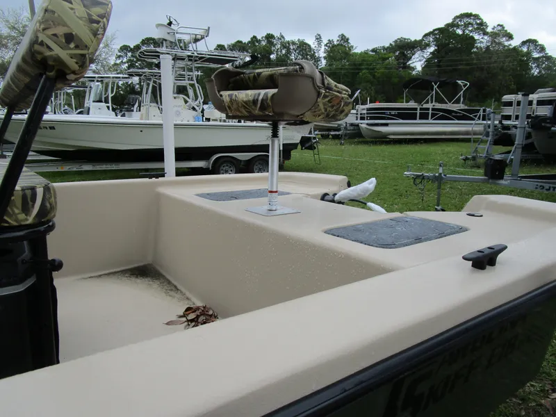 Slide: The Image of 2025 Carolina Skiff E Series E18 JVX CC boat with camo seats, parked on grass. - 4