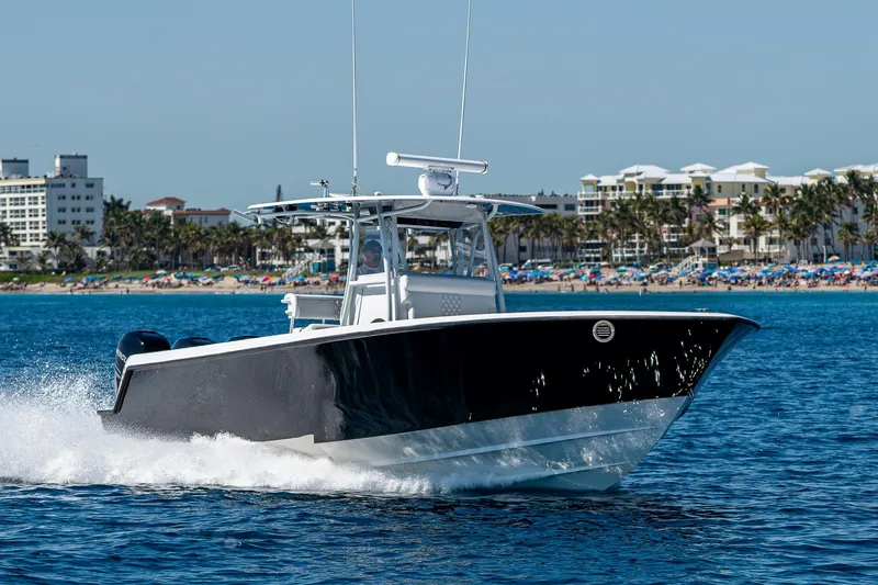 Slide: The Image of 2017 Contender 39 ST boat cruising on blue water near a beachside cityscape. - 30