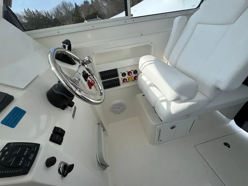 Slide: The Image of 2025 NorthCoast 255 HT boat interior with steering wheel and white captain's seat. - 16