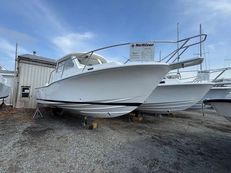 Slide: The Image of 2025 NorthCoast 255 HT boat on display, white hull, parked on gravel lot. - 3