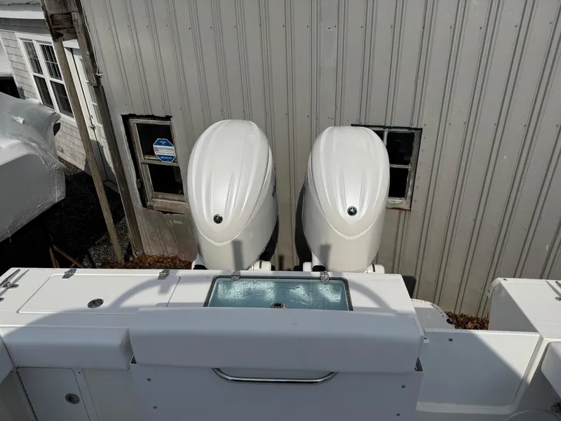 Slide: The Image of 2025 NorthCoast 255 HT boat with dual outboard engines, docked near a building. - 6