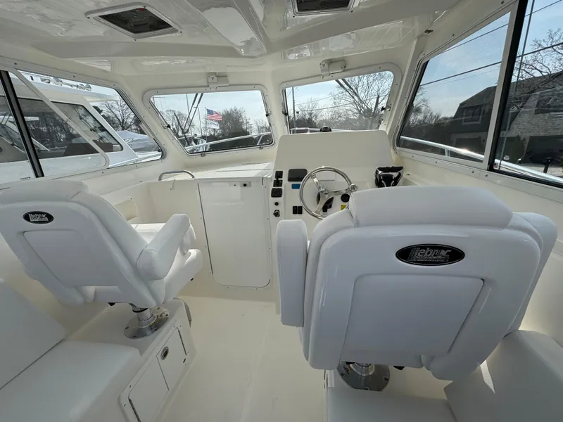 Slide: The Image of Interior of 2025 NorthCoast 255 HT boat with white seating and modern dashboard. - 8