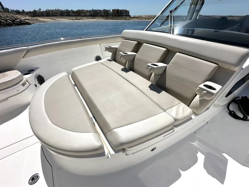 Slide: The Image of 2020 Boston Whaler 420 Outrage boat with luxurious seating and cup holders, docked by the water. - 13