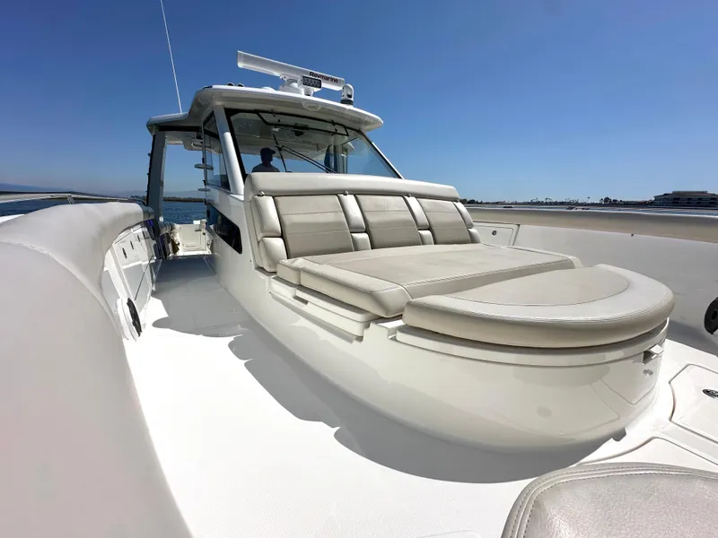 Slide: The Image of 2020 Boston Whaler 420 Outrage boat with spacious deck and seating under clear blue sky. - 22