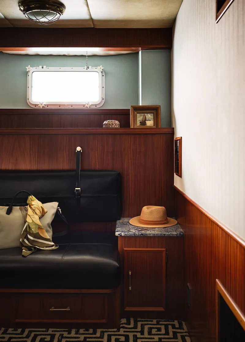 Slide: The Image of Interior of 1981 Hatteras Motor Yacht with wood paneling, black seating, and decorative items. - 25