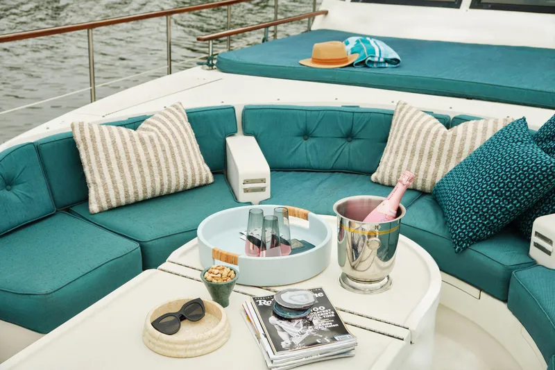 Slide: The Image of Luxurious 1981 Hatteras Motor Yacht deck with teal seating, champagne, and stylish decor. - 27