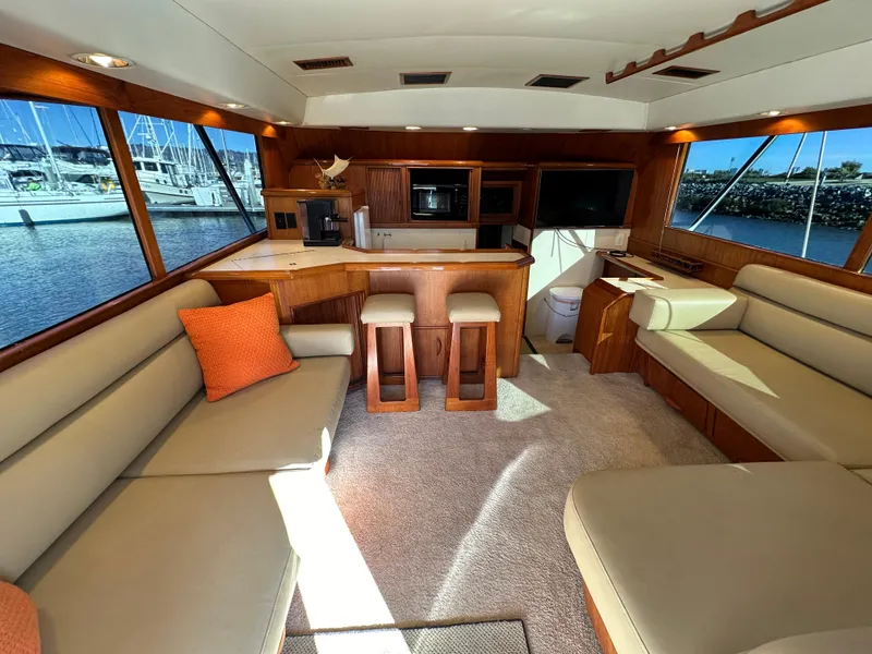 Slide: The Image of 1988 Buddy Davis Convertible yacht interior with beige seating, wooden accents, and marina view. - 11
