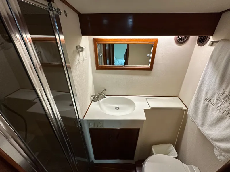 Slide: The Image of Compact bathroom in a 1988 Buddy Davis Convertible yacht, featuring a sink, mirror, and shower. - 35