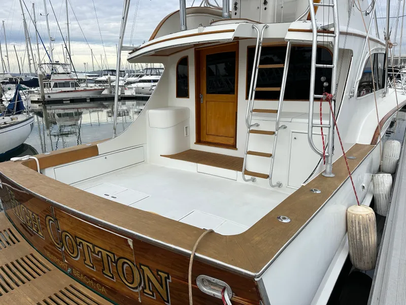Slide: The Image of 1988 Buddy Davis Convertible yacht docked at marina, featuring spacious deck and wooden accents. - 5