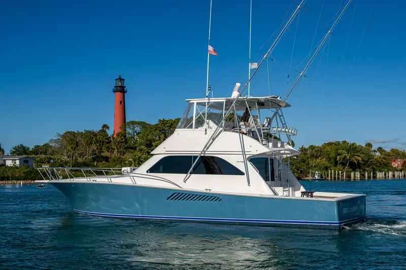 Slide: The Image of 2005 Viking 52 Convertible yacht cruising near a lighthouse on a sunny day. - 2
