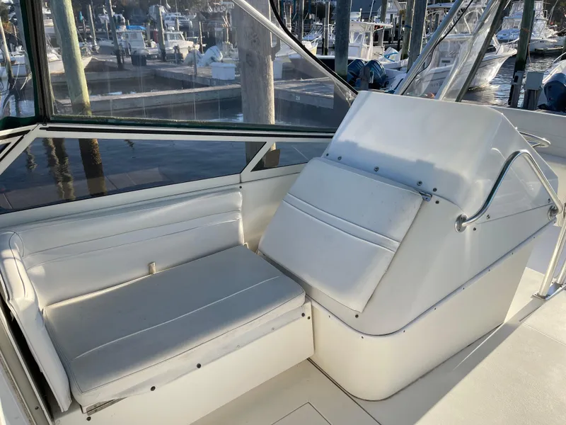 Slide: The Image of 1999 Contender 35 Express Side Console with white seating and helm, docked at marina. - 17