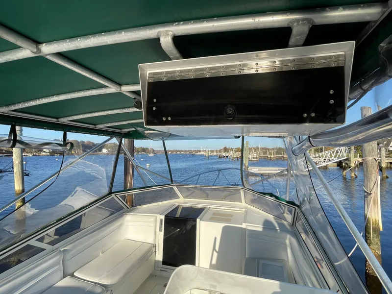 Slide: The Image of 1999 Contender 35 Express Side Console boat with green canopy, docked by the water. - 23