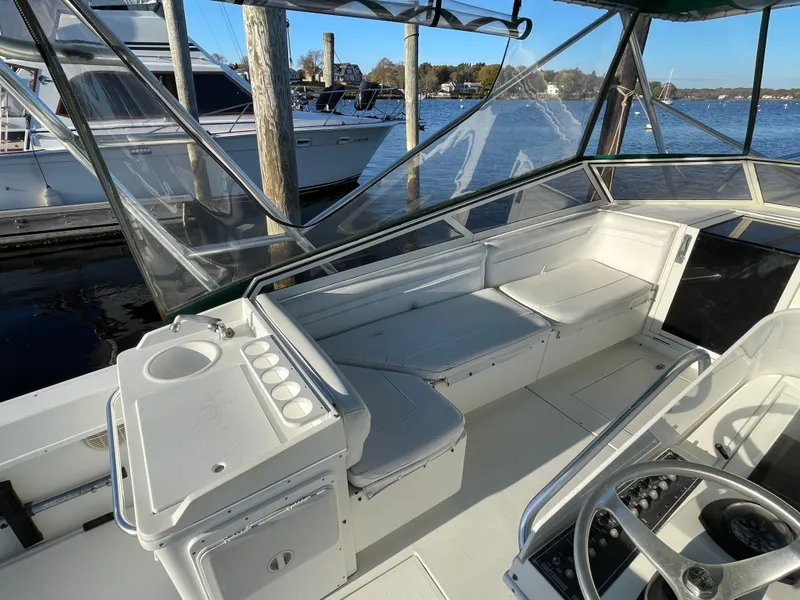 Slide: The Image of 1999 Contender 35 Express Side Console boat interior with seating and helm, docked by the water. - 24