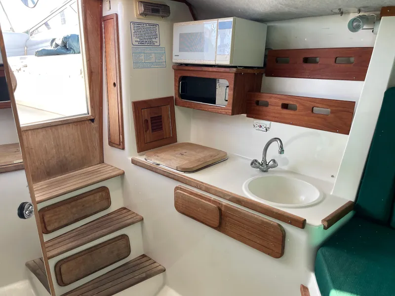 Slide: The Image of 1999 Contender 35 Express Side Console interior with kitchenette, microwave, sink, and wooden accents. - 28