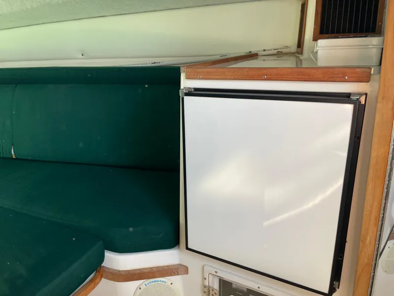 Slide: The Image of Interior of 1999 Contender 35 Express Side Console with green seating and a compact fridge. - 34