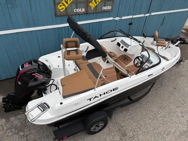 Slide: The Image of 2025 Tahoe 185 S boat with tan seating and black motor, parked on trailer. - 4