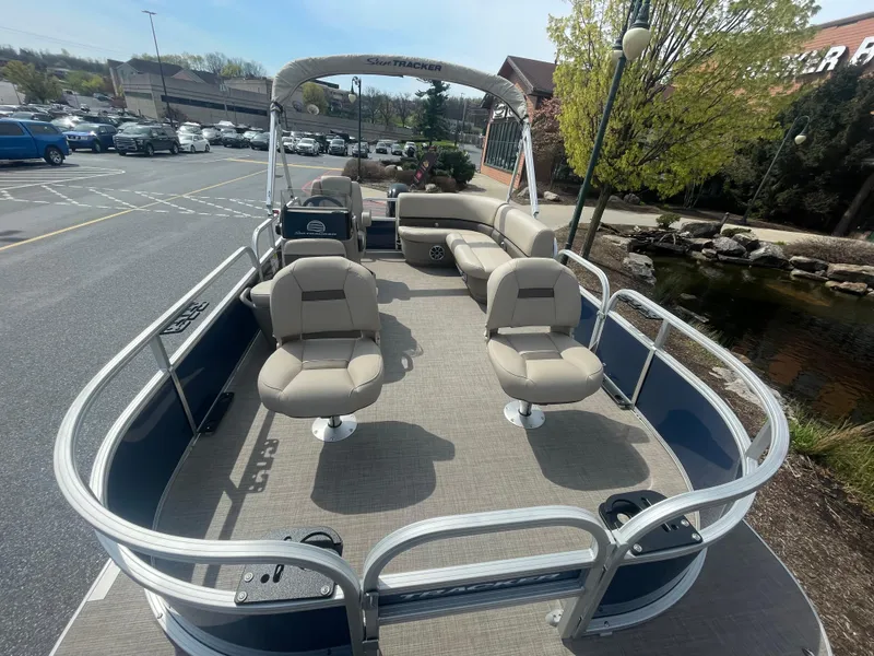 Slide: The Image of 2025 Sun Tracker Bass Buggy 16 XL Select pontoon boat with seating, parked outdoors. - 2