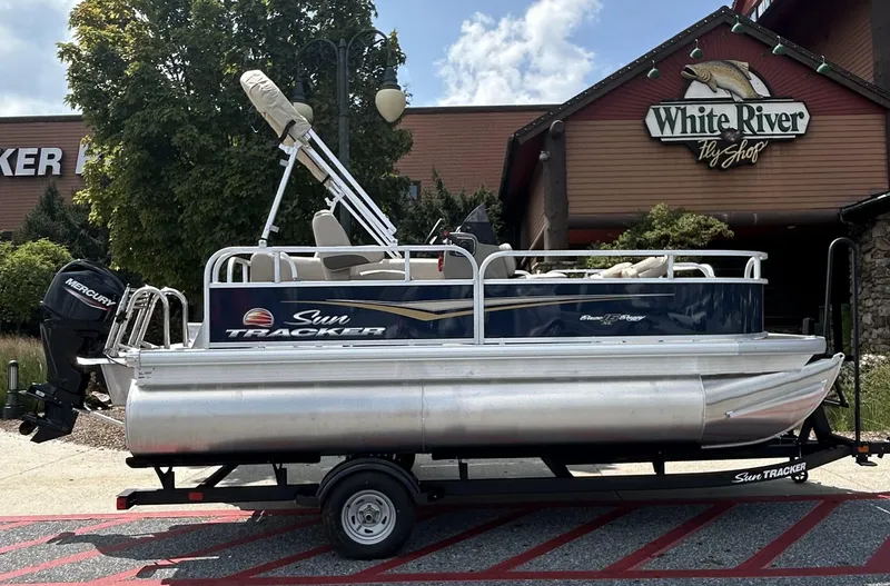 Slide: The Image of 2025 Sun Tracker Bass Buggy 16 XL Select pontoon boat on trailer outside White River Fly Shop. - 3