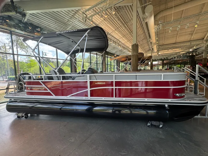 Slide: The Image of 2025 Ranger Reata 220C pontoon boat displayed indoors with a sleek red and black design. - 1