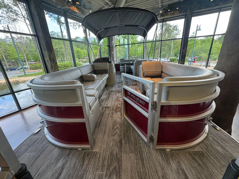 Slide: The Image of 2025 Ranger Reata 220C pontoon boat with spacious seating and canopy, displayed indoors. - 2