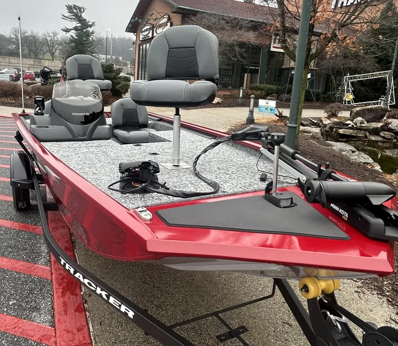 Slide: The Image of 2025 Tracker Pro 170 fishing boat with red exterior and gray seating, parked outdoors. - 2