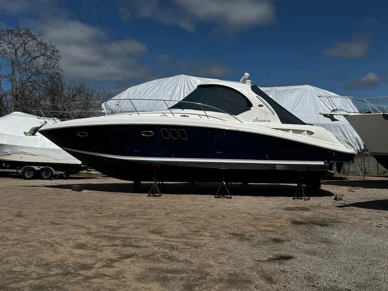 The Image of 2006 Sea Ray 380 Sundancer yacht on stands, outdoor storage, clear sky. - 0