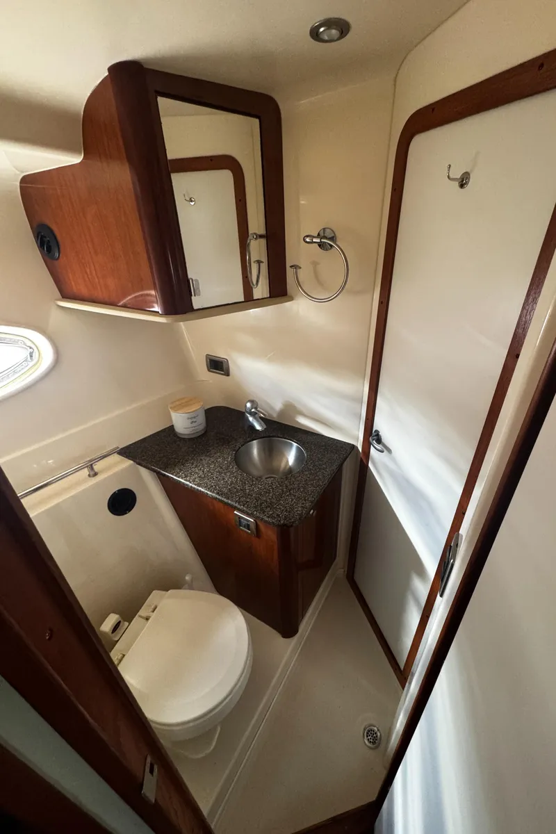 Slide: The Image of 2006 Sea Ray 380 Sundancer bathroom with sink, toilet, and wooden cabinetry. - 20