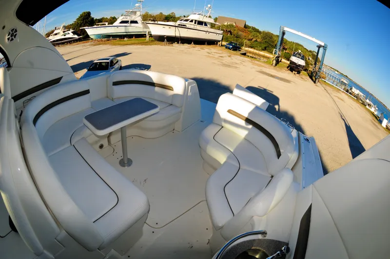 Slide: The Image of 2006 Sea Ray 380 Sundancer boat interior with white seating and table, docked near other boats. - 7