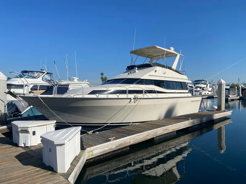 The Image of 1991 Mainship 41 Convertible yacht docked at marina under clear blue sky. - 0