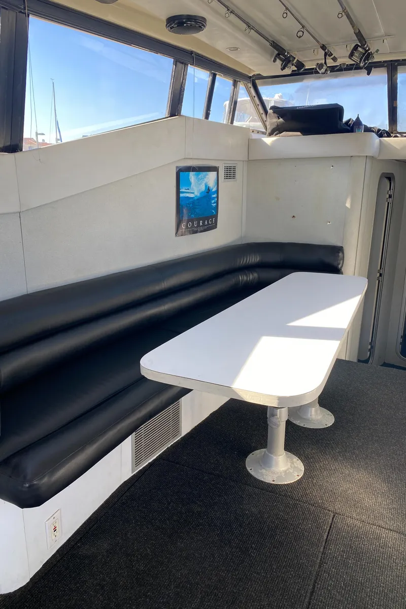 Slide: The Image of 1991 Mainship 41 Convertible interior with black seating and white table. - 15