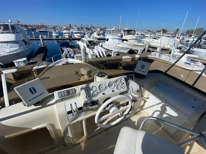 Slide: The Image of 1991 Mainship 41 Convertible yacht helm with marina view, featuring navigational instruments and steering wheel. - 4