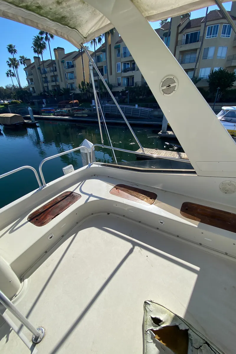 Slide: The Image of 1991 Mainship 41 Convertible yacht deck with marina view and residential backdrop. - 8