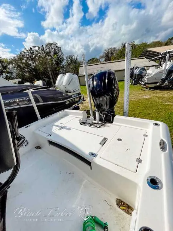 Slide: The Image of 2022 Tidewater 2210 Carolina Bay boat with outboard motor, parked outdoors under a cloudy sky. - 9