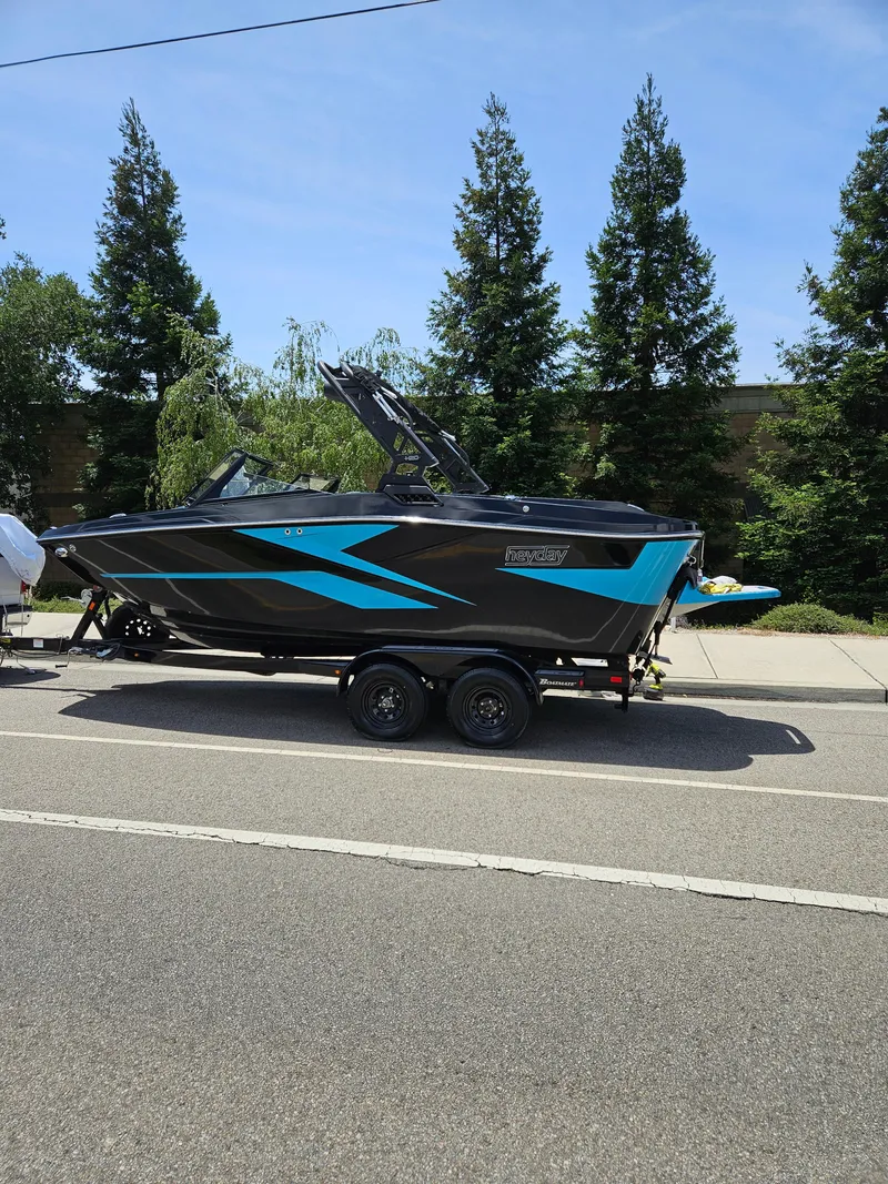 Slide: The Image of 2023 HEYDAY WAKE BOATS H20 on trailer, parked roadside with trees in background. - 17
