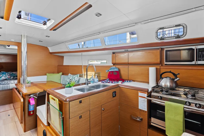 Slide: The Image of Modern kitchen interior of 2020 Jeanneau Sun Odyssey 389 yacht with wood cabinetry and appliances. - 14