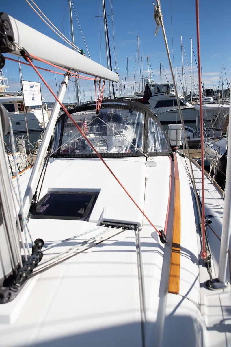 Slide: The Image of 2020 Jeanneau Sun Odyssey 389 sailboat docked in a marina, showcasing sleek design and rigging. - 5