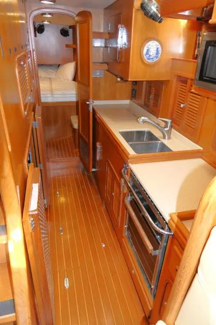 Slide: The Image of 2002 Tayana 460 Vancouver Pilothouse interior with wood finish, kitchen, and cozy sleeping area. - 31