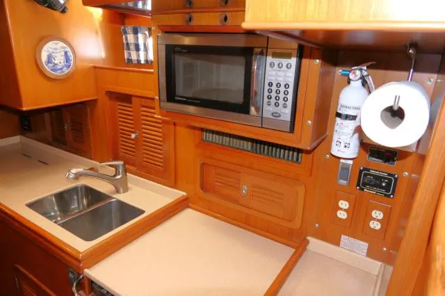 Slide: The Image of Tayana 460 Vancouver Pilothouse 2002 galley with microwave, sink, and wooden cabinetry. - 36