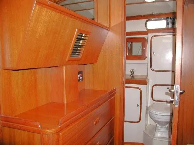 Slide: The Image of Interior of 2002 Tayana 460 Vancouver Pilothouse, featuring wooden cabinetry and compact bathroom. - 48